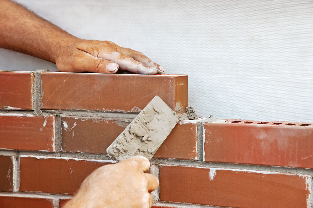 hand laying bricks with tool