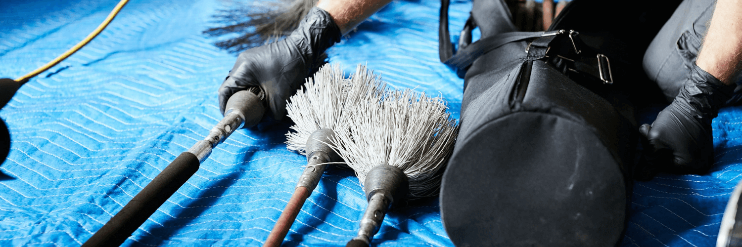 Hand holding chimney sweep brushes